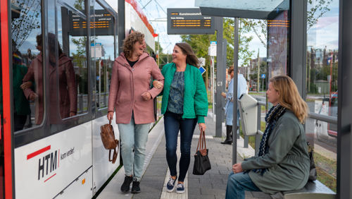Reizigers lopen op tramhalte Reizigers lopen op halte naast HTM tram