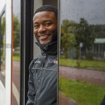 BOA controleur staat in deuropening van tram HTM boa staat in deuropening HTM tram en lacht naar de camera