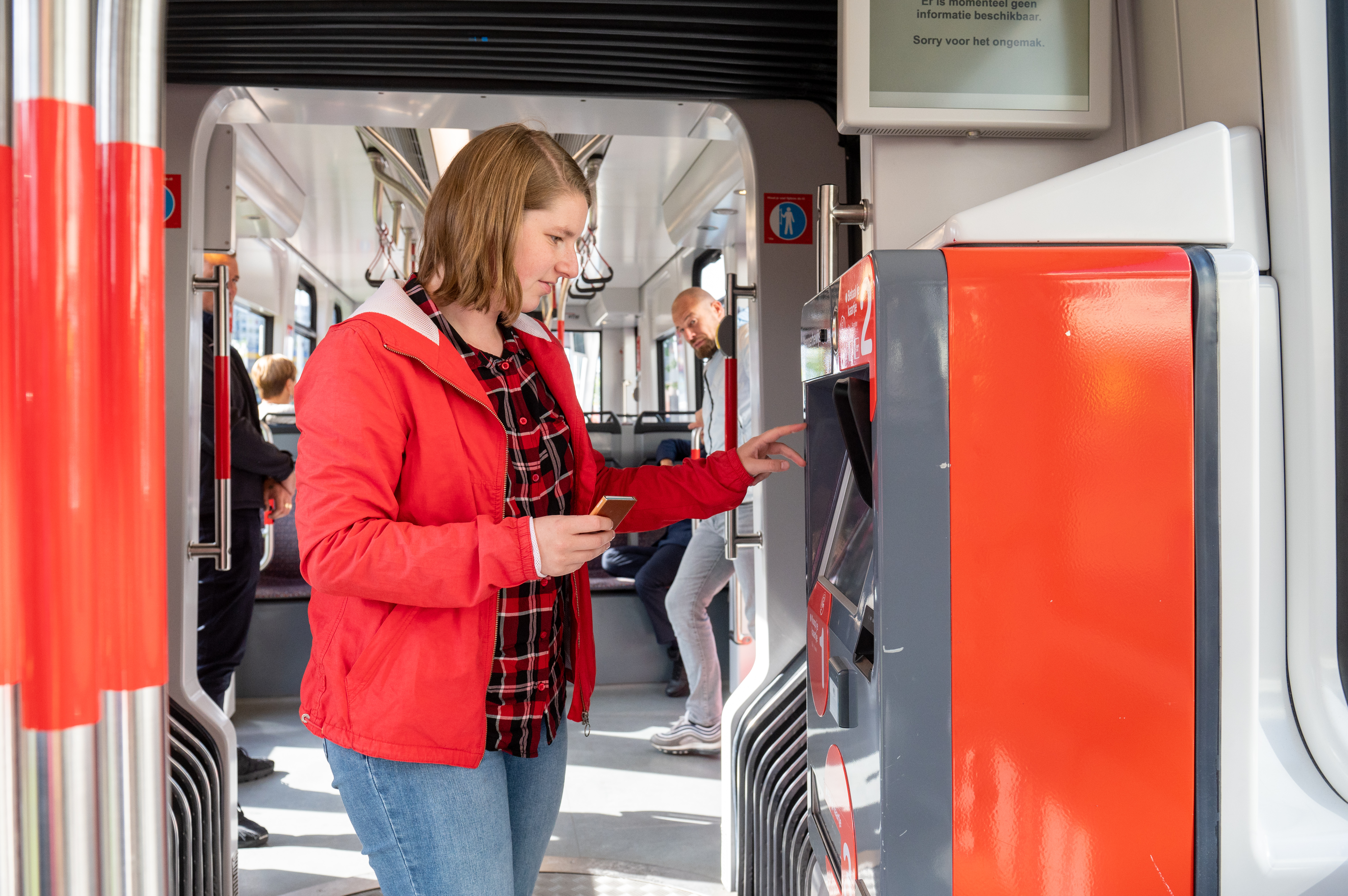 Vrouw koopt kaartje bij HTM kaartverkoopautomaat in HTM tram
