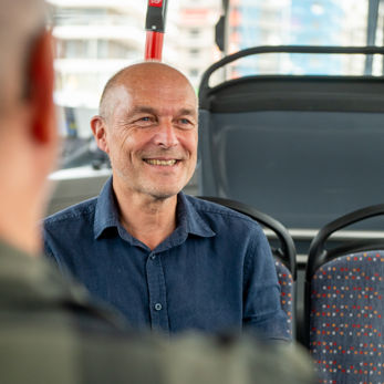 Reiziger zit in HTM bus Man zit in HTM bus en kijkt naar voren