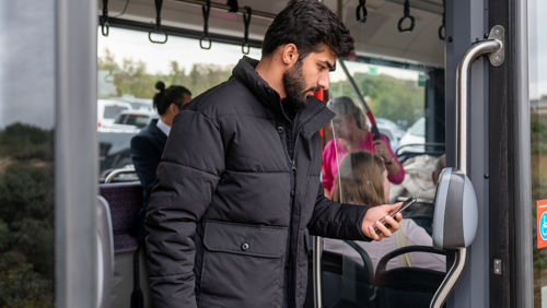 Man checkt uit met telefoon Reiziger checkt uit met OV-pay in HTM tram