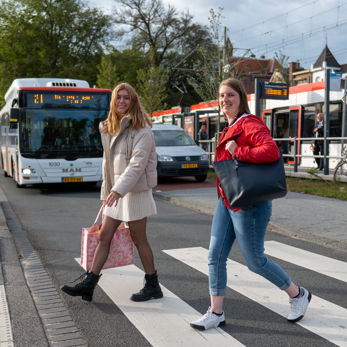 Reizigers naast tramhalte Reizigers steken de straat over naast HTM tramhalte