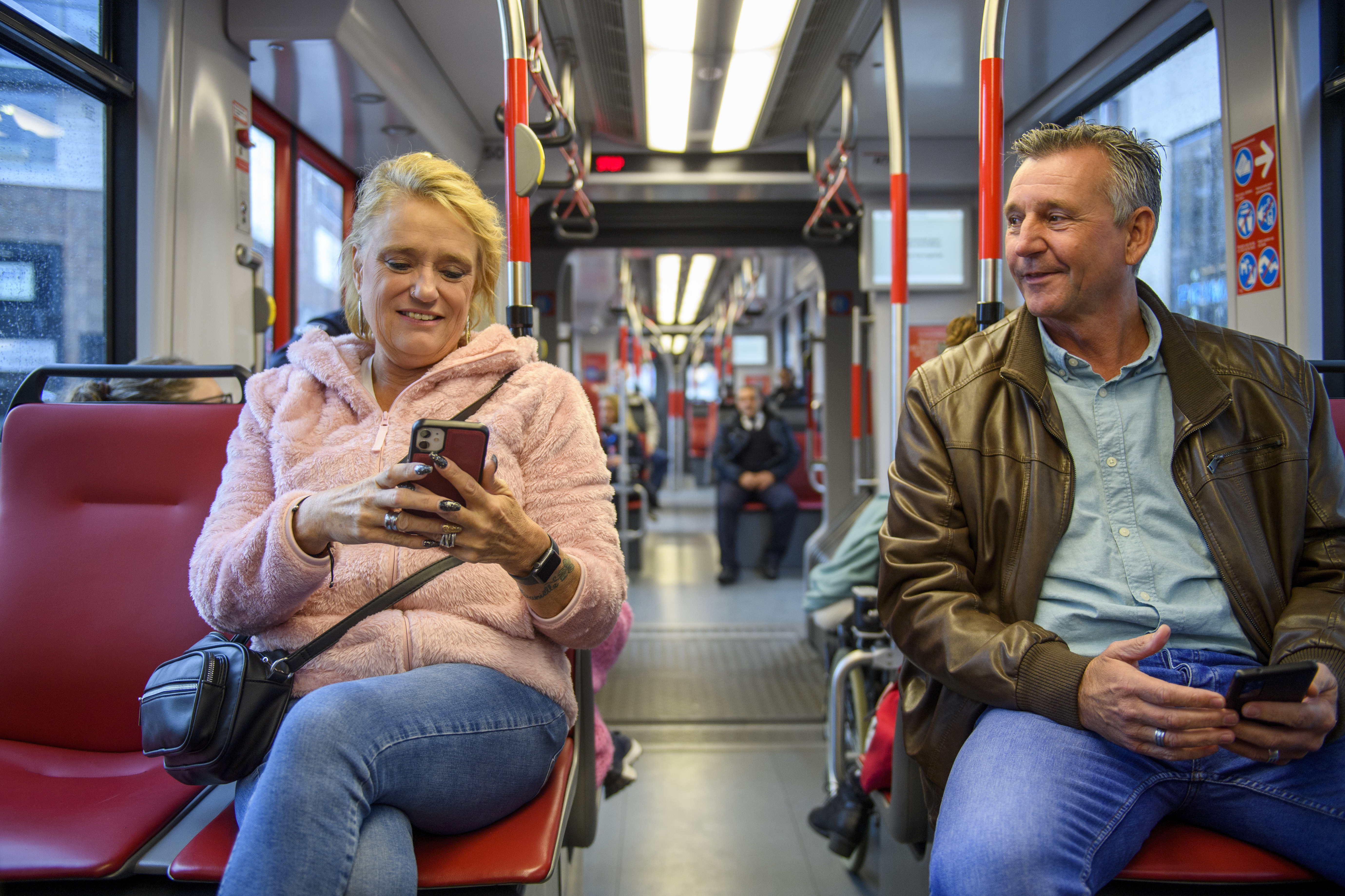 Man zit naast vrouw die op de telefoon kijkt in HTM tram