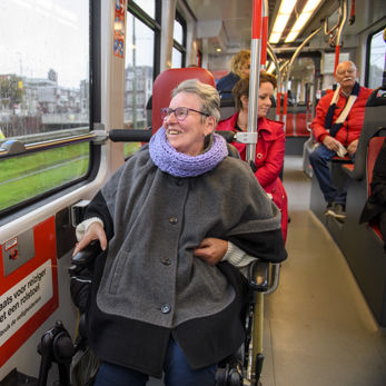 Reiziger in een rolstoel zit in HTM tram en kijkt naar buiten Reiziger in een rolstoel zit in HTM tram en kijkt naar buiten