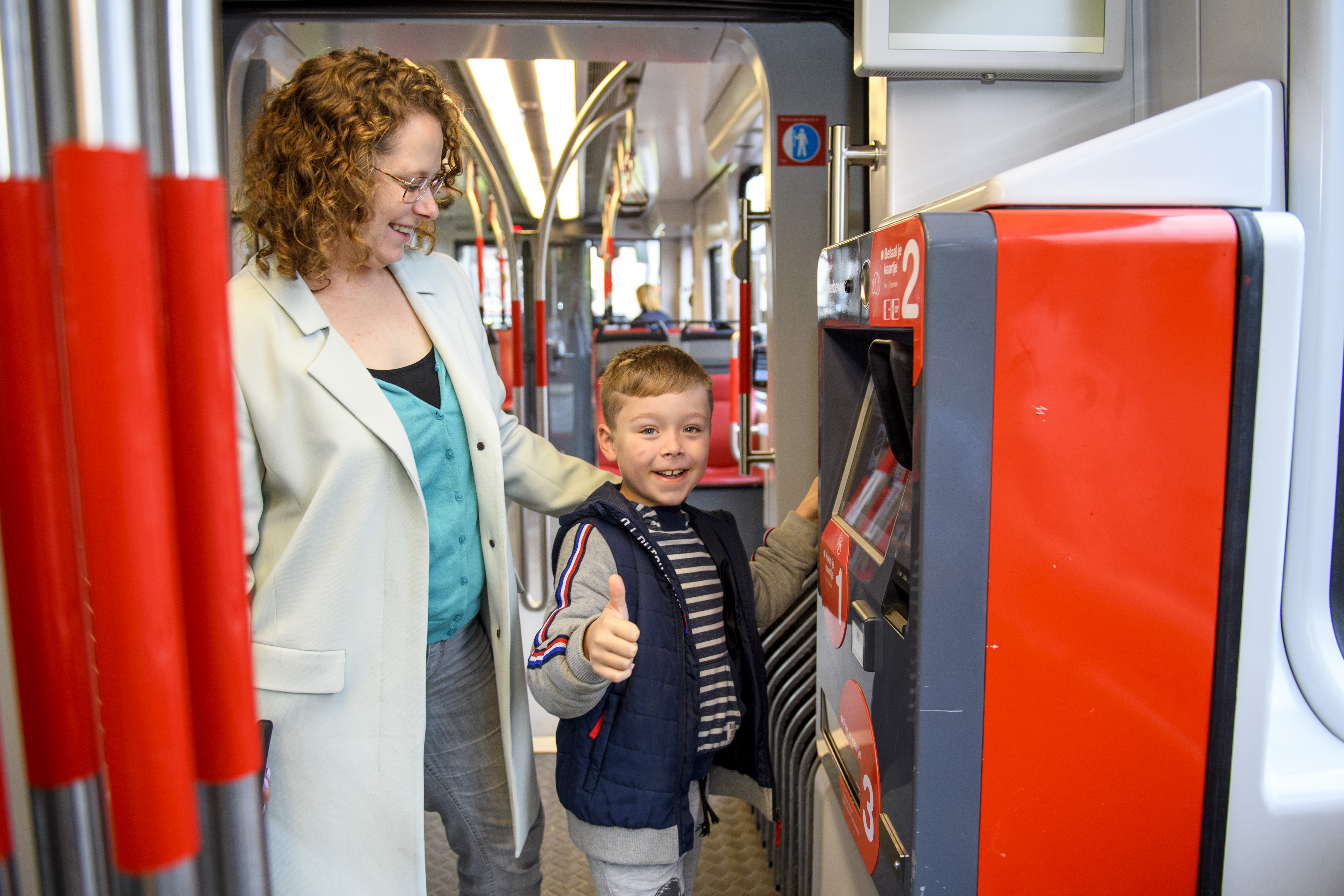 Moeder en kind kopen tramkaartje bij kaartverkoopautomaat in HTM tram
